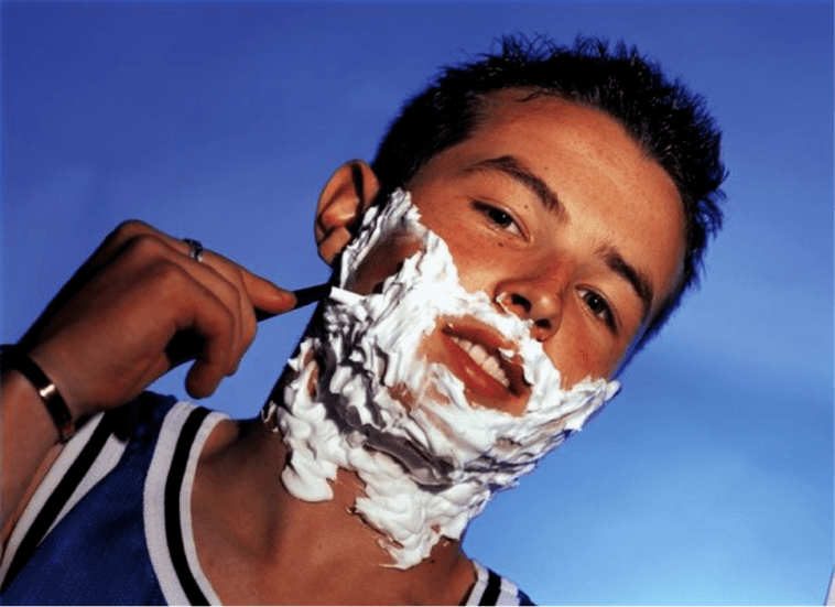 un adolescent se rase et réfléchit à l'agrandissement du pénis